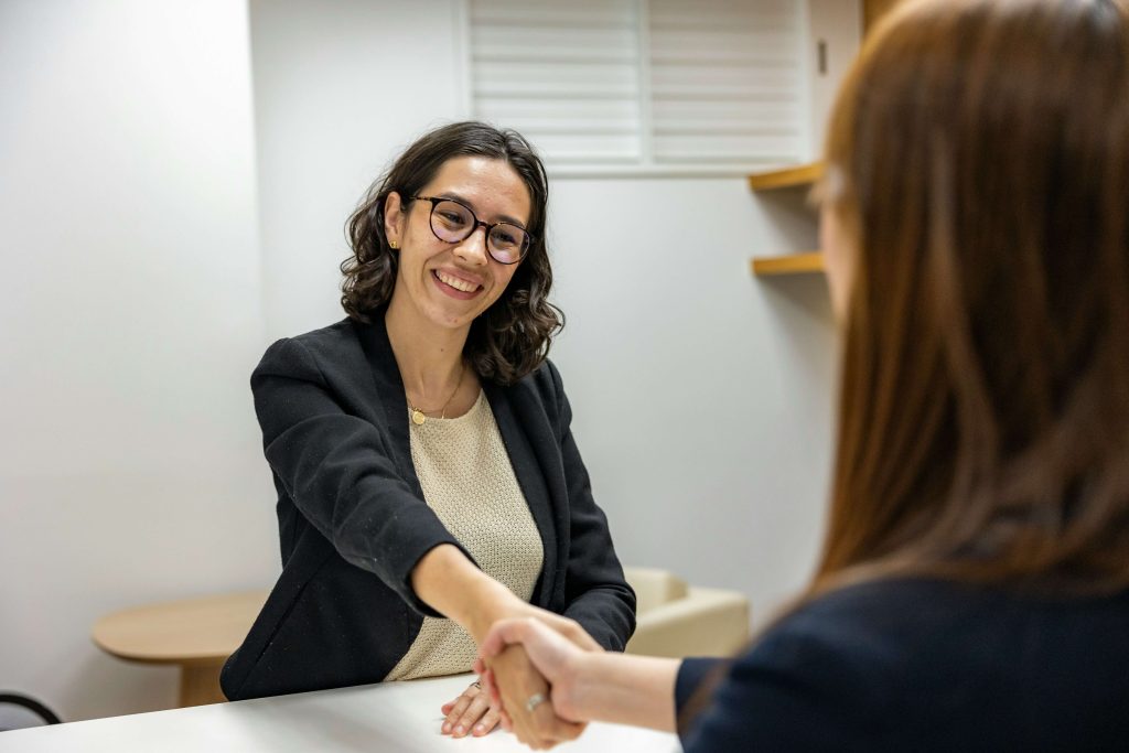 Candidata y reclutadora estrechando la mano al finalizar proceso de selección dentro de un plan de reclutamiento estratégico